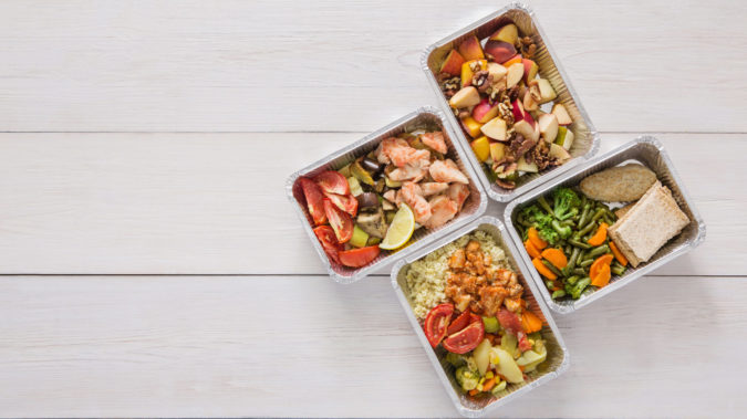 Healthy food take away in boxes, top view at wood