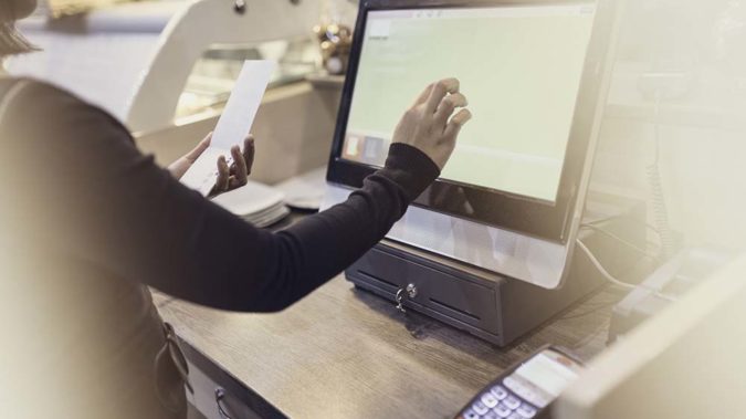 Waitress using touchscreen computer at the bar counter